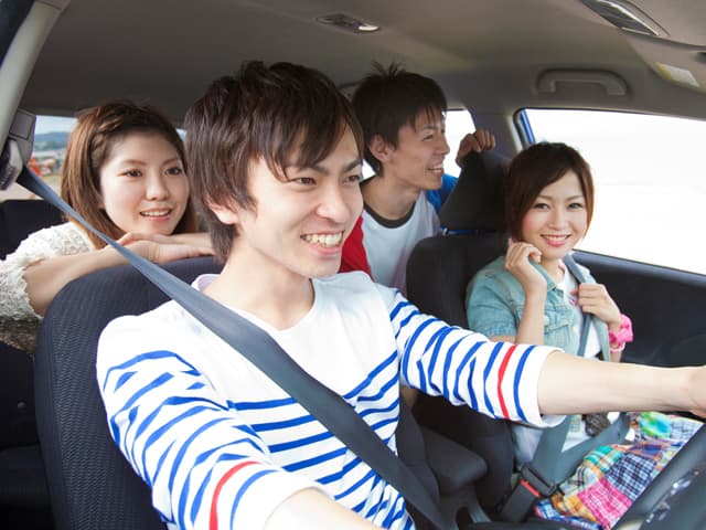 男女が笑顔で車の運転をしている